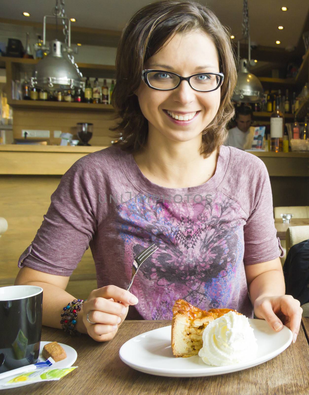 Smiling woman at cafe eating apple cake dessert with cream