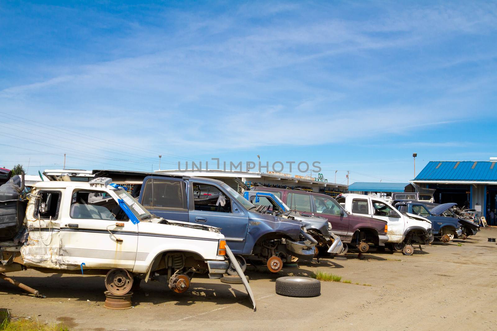 The scene shows many cars and other automobiles in a salvage junk yard where customers can pick and choose part for their vehicle repairs.