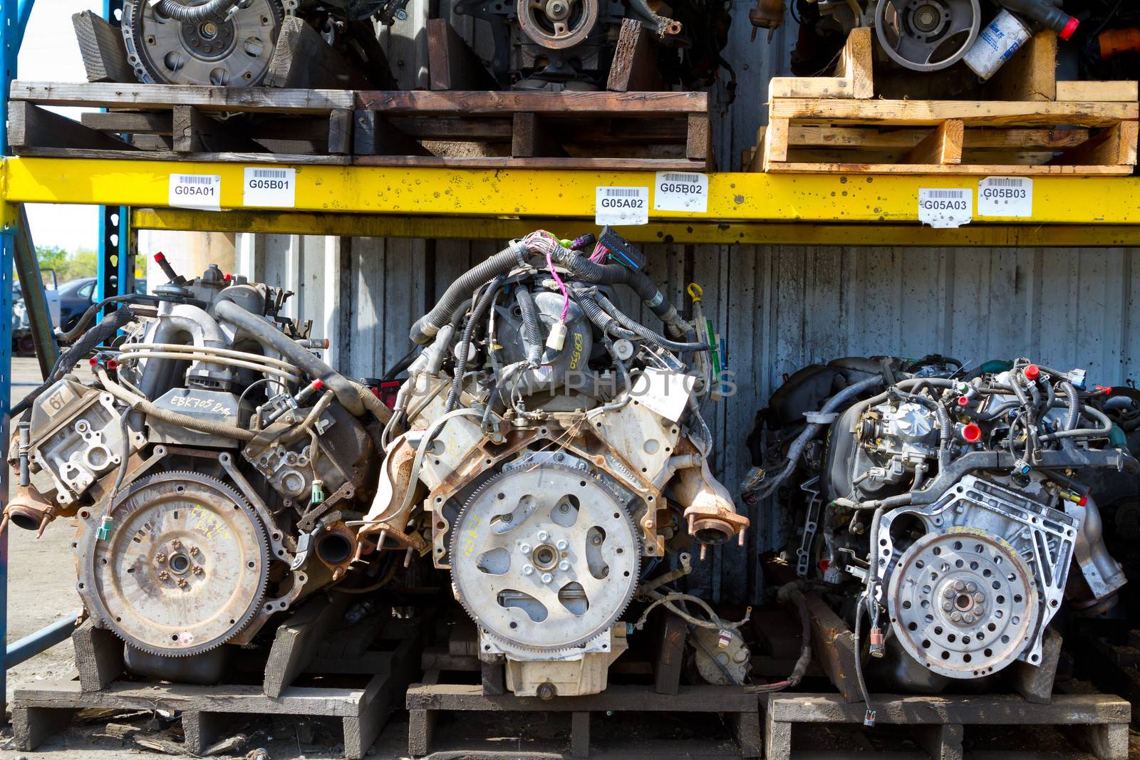 Car and truck engine block motors are lined up at an automobile salvage yard junkyard.