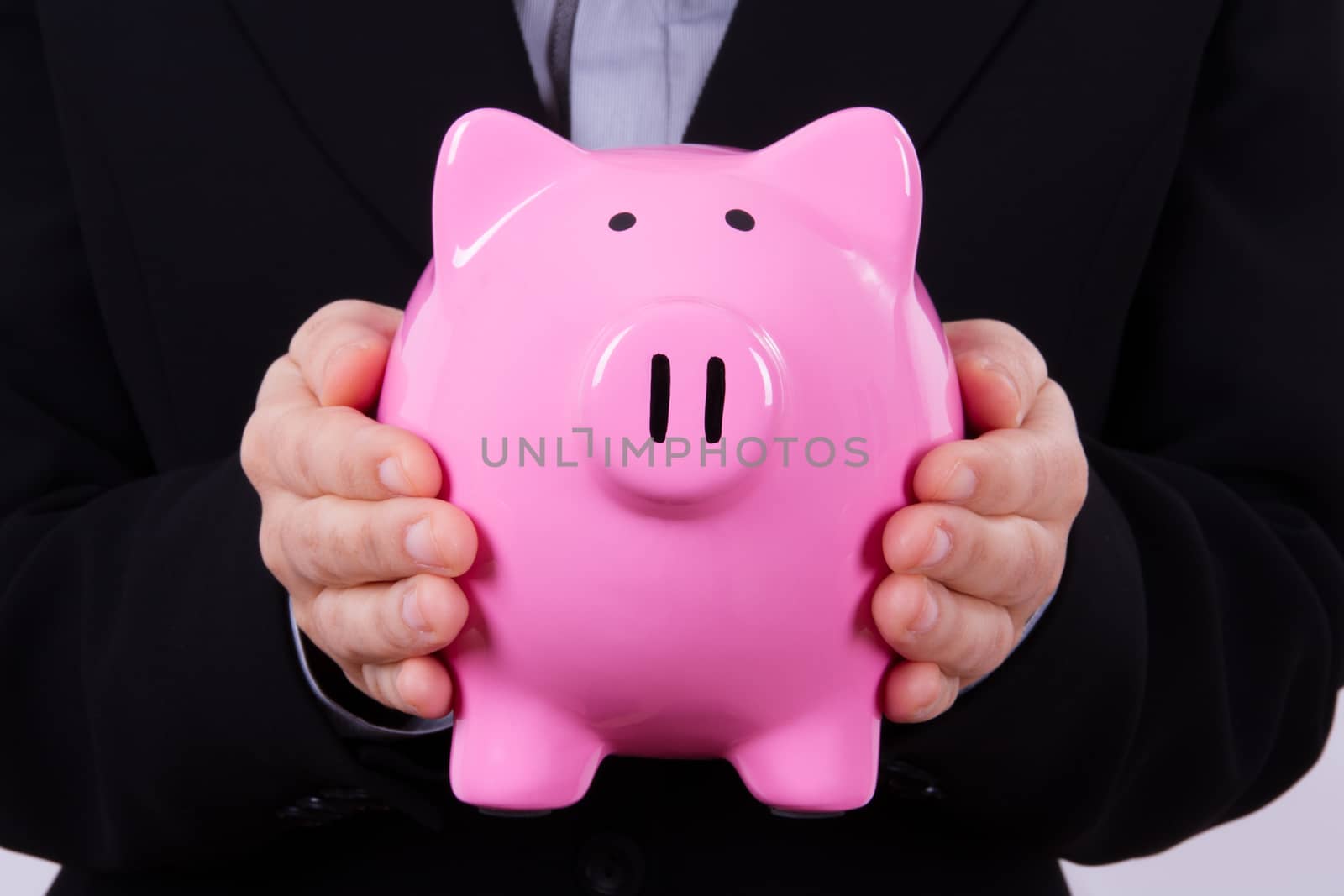 Business woman holding pink piggy bank between hands.