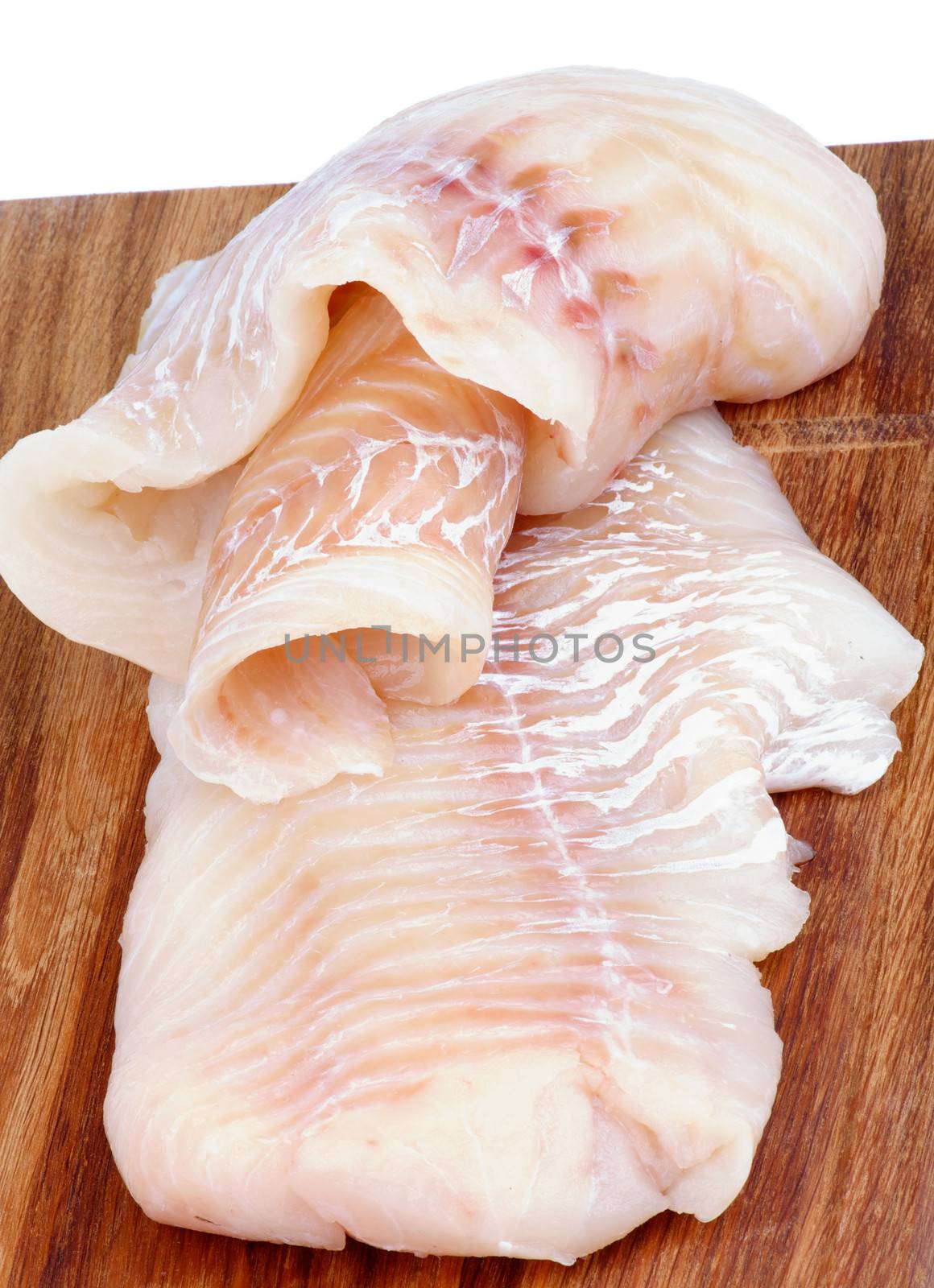 Two Slices of Raw Cod Fish Fillet closeup on Wooden Cutting Board on white background