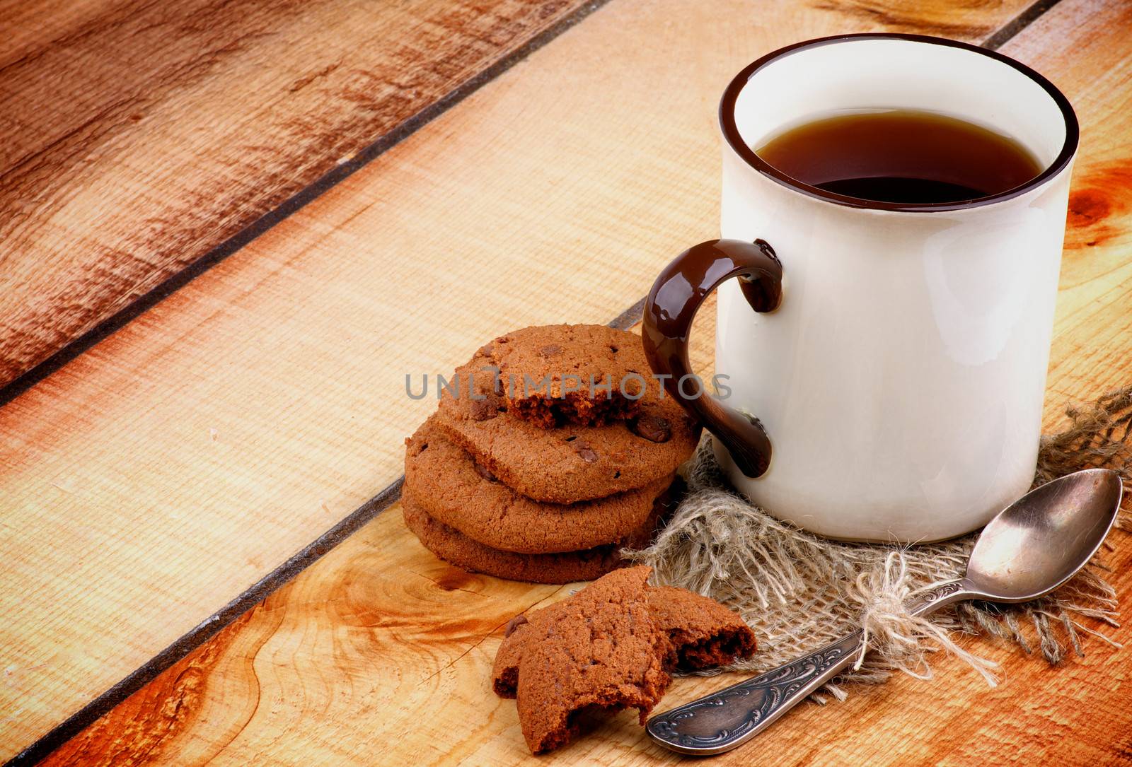 Rustic Cup of Black Tea with Chocolate Chip Cookies and Tea Spoon on Wooden background as Frame