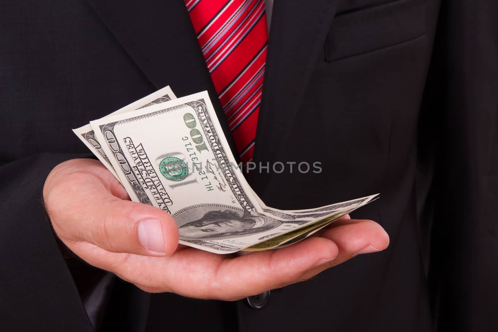 Businessman with red striped tie and dark jacket, holding money.