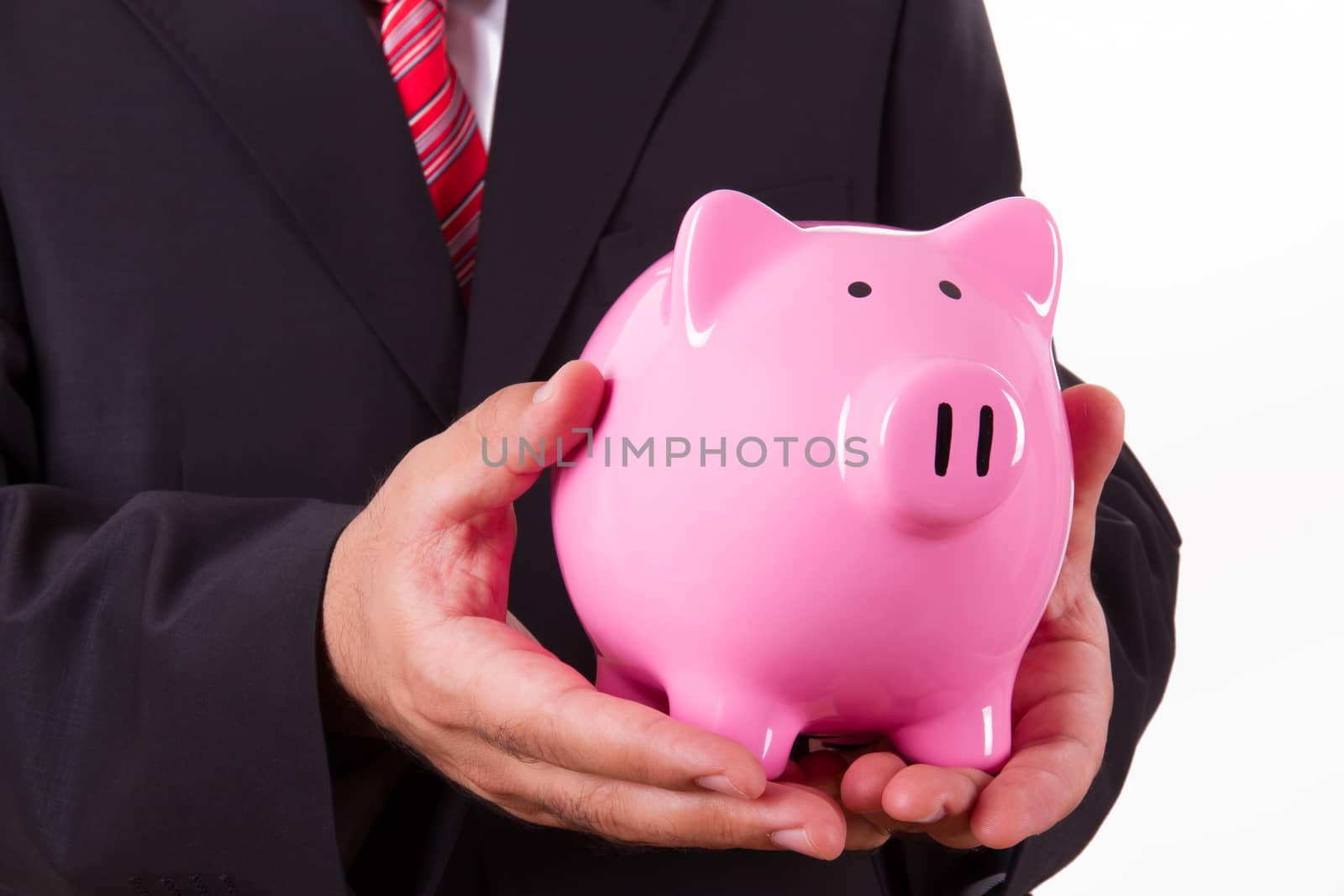 Businessman in suit holding pink piggy bank with both hands, isolated on white background.