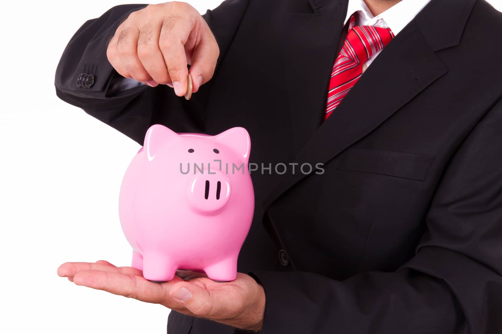 Businessman putting coin into pink piggy bank, isolated on white background.