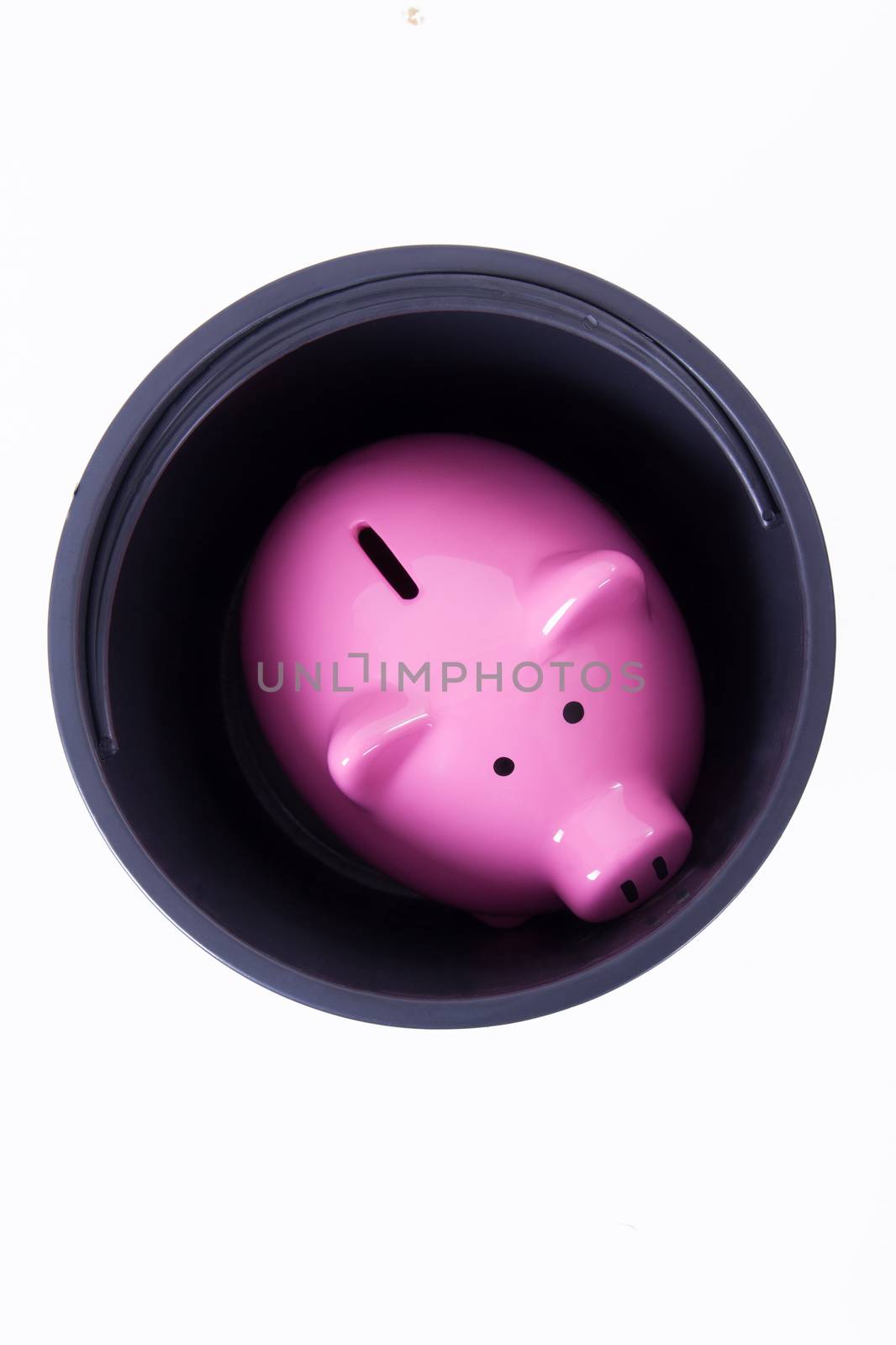 Pink piggy bank stacked in black bucket, top view, isolated on white background.