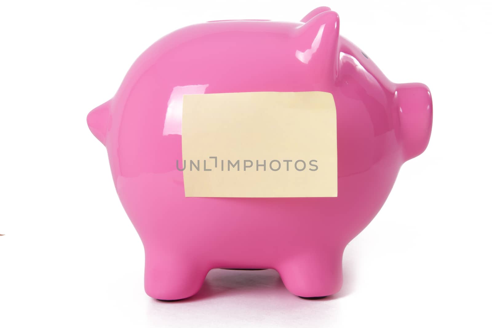 Pink piggy bank with yellow sitcky note, isolated on white background.