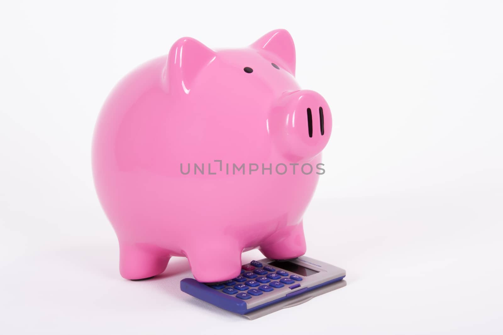 Pink piggy bank on the calculator, isolated on white background.