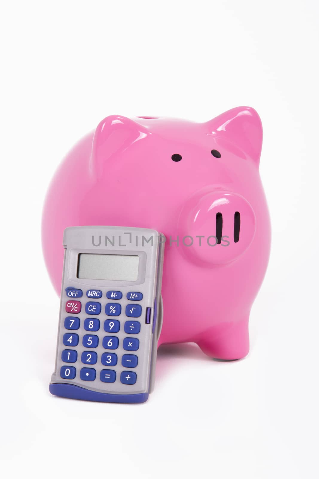 Calculator leans to pink piggy bank, isolated on white background.