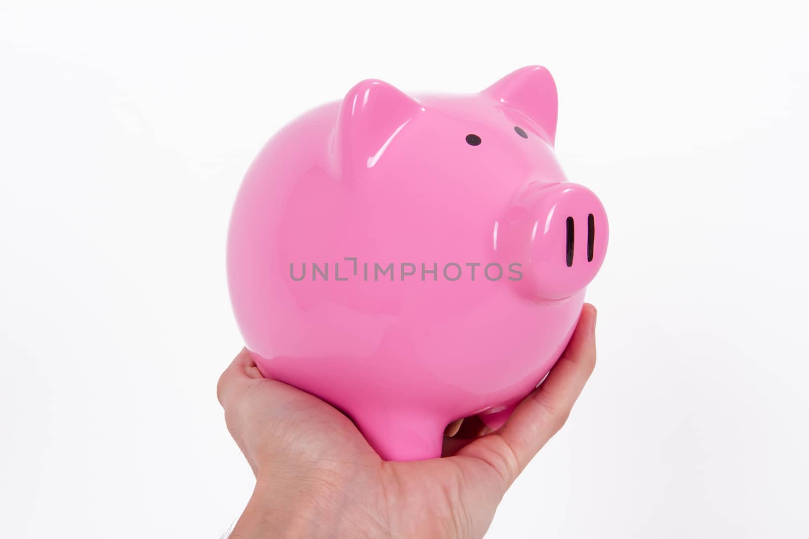 Human hand holding pink piggy bank, isolated on white background.