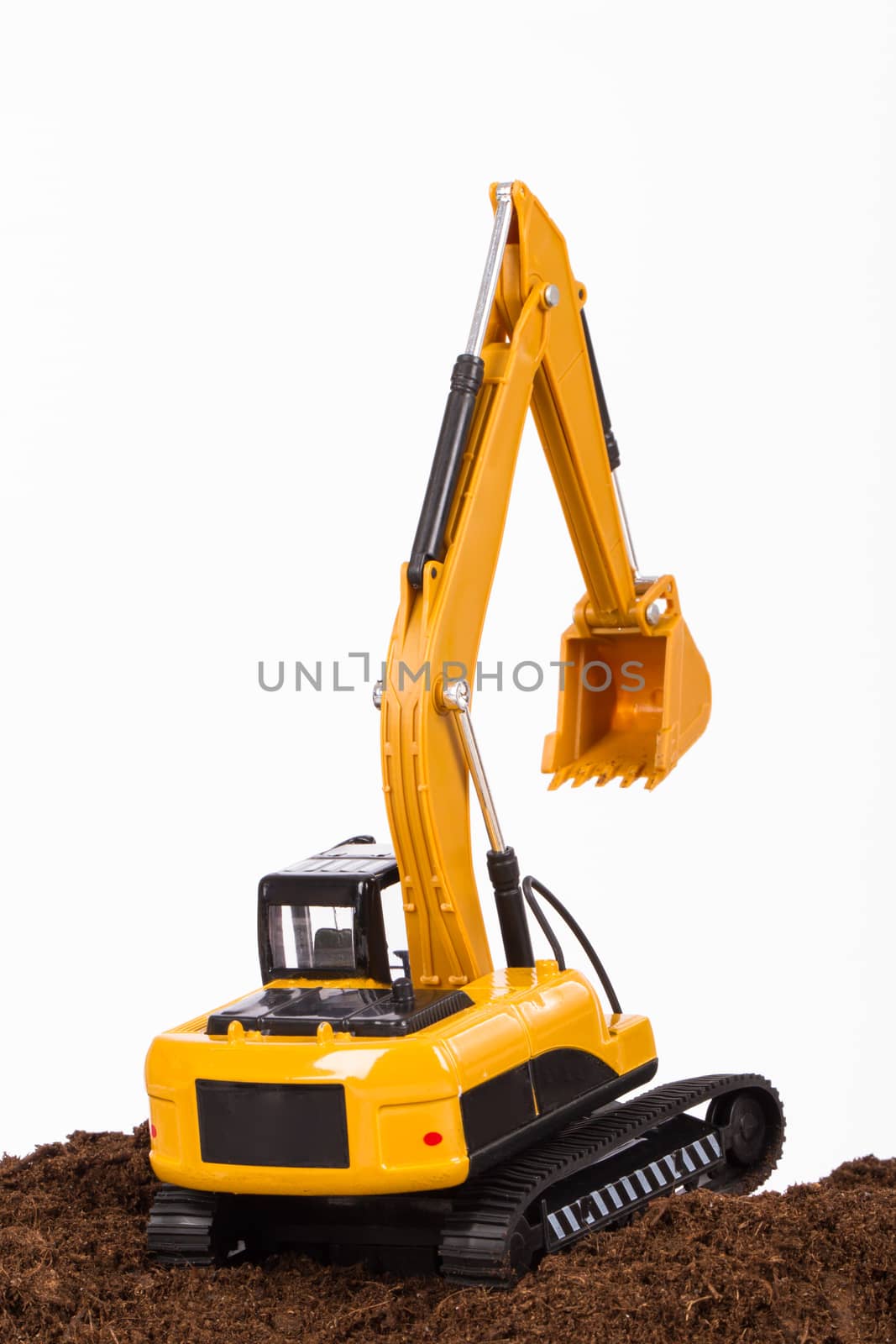 Construction machine, excavator on pile of soil digging a trench, isolated on white background.