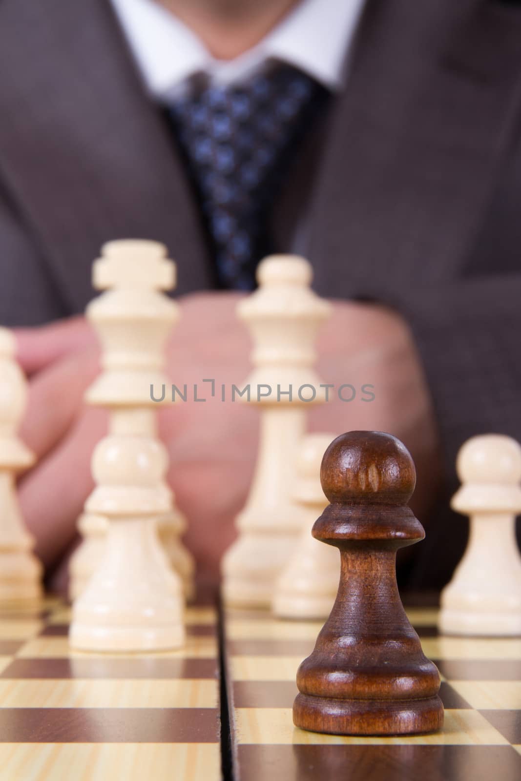 Close up to chess pawn front of businessman and other chess pieces on board.