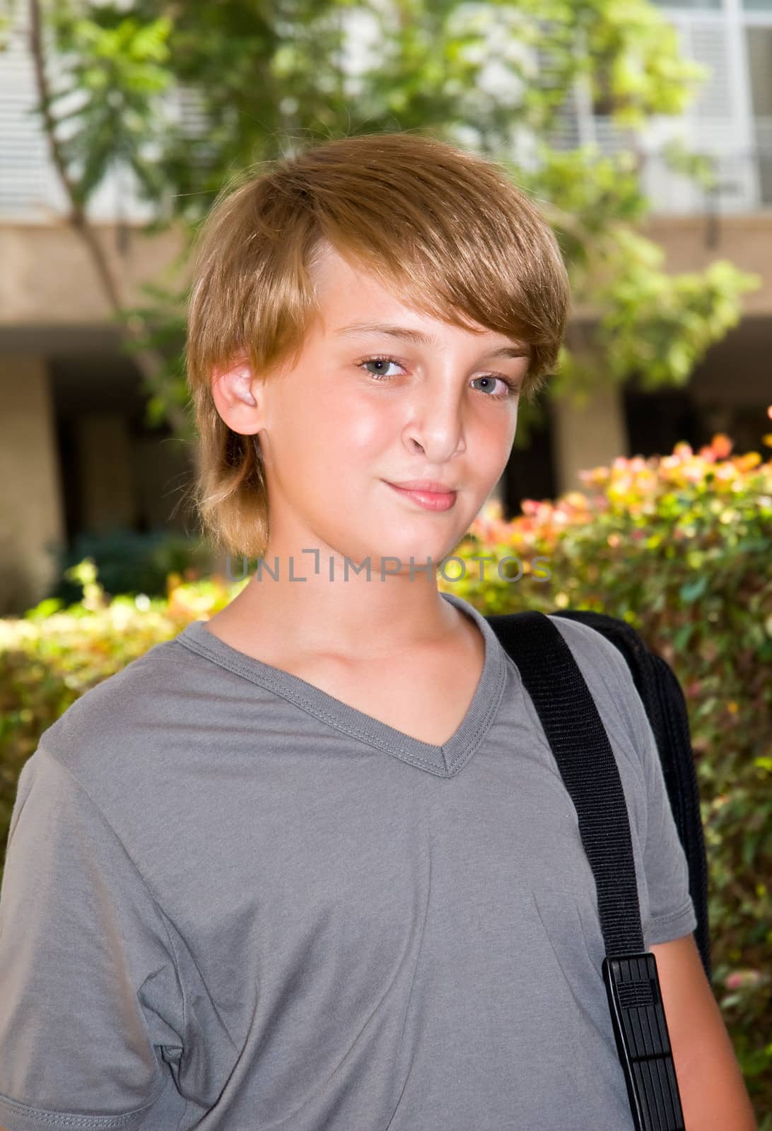 Portrait of young boy standing with a bag .