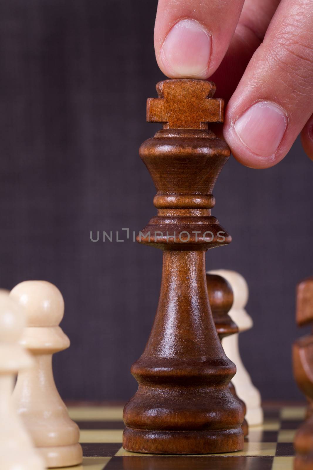 Businessman playing chess and holding king chess piece on board.