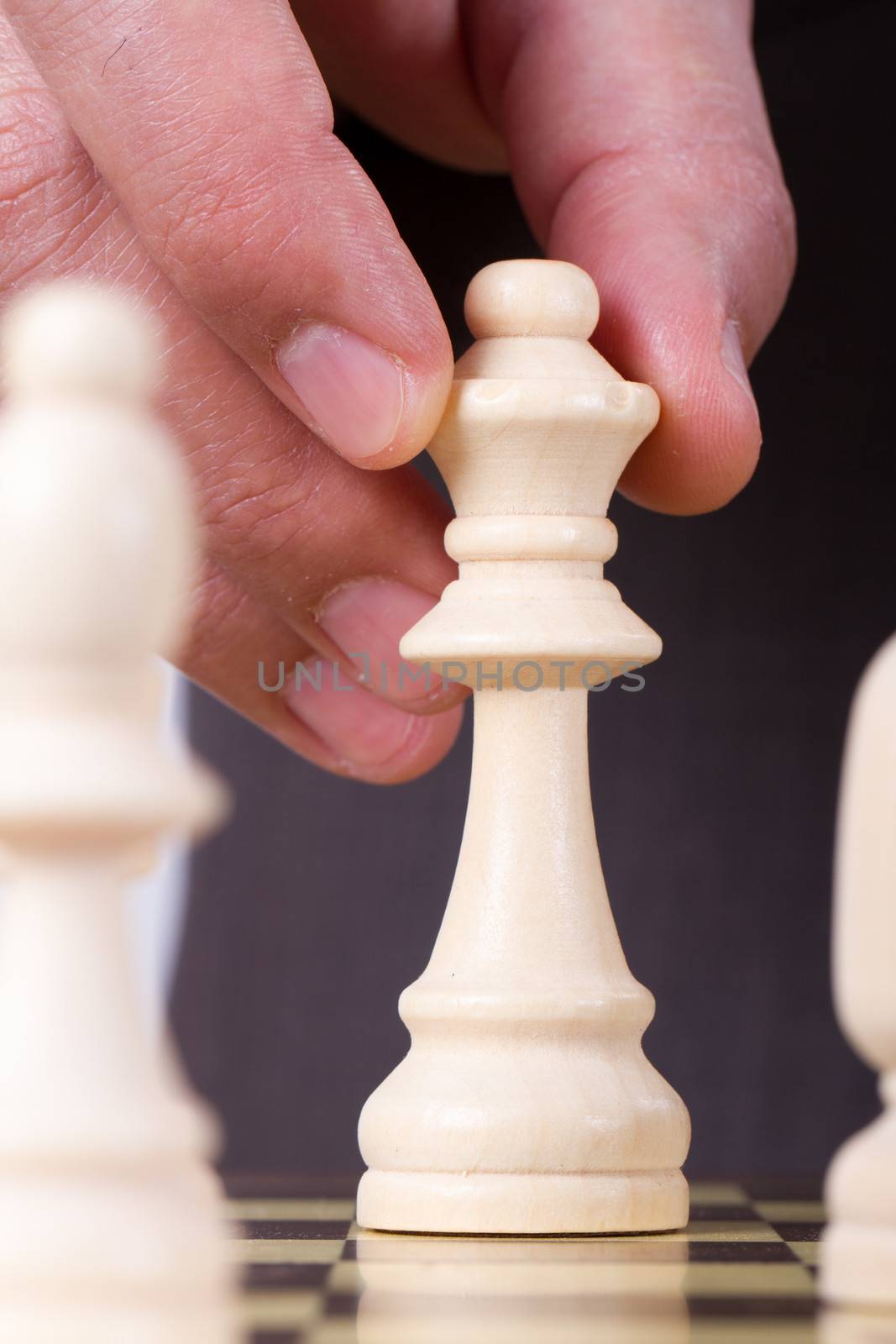 Businessman playing chess and holding queen chess piece.