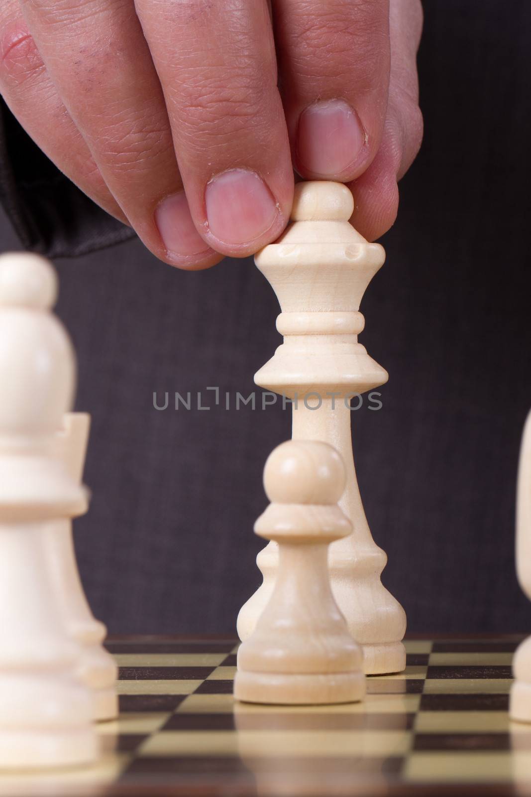 Businessman playing chess and holding queen chess piece.