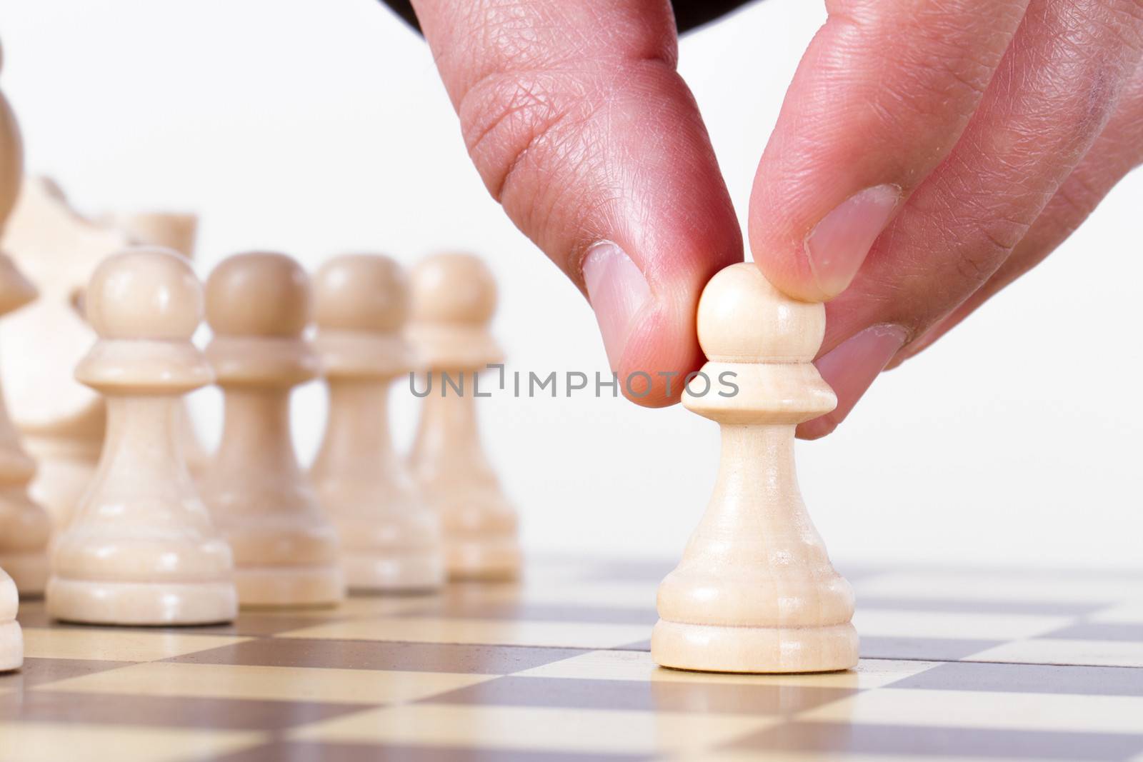 Businessman playing chess and holding pawn, isolated on white background.