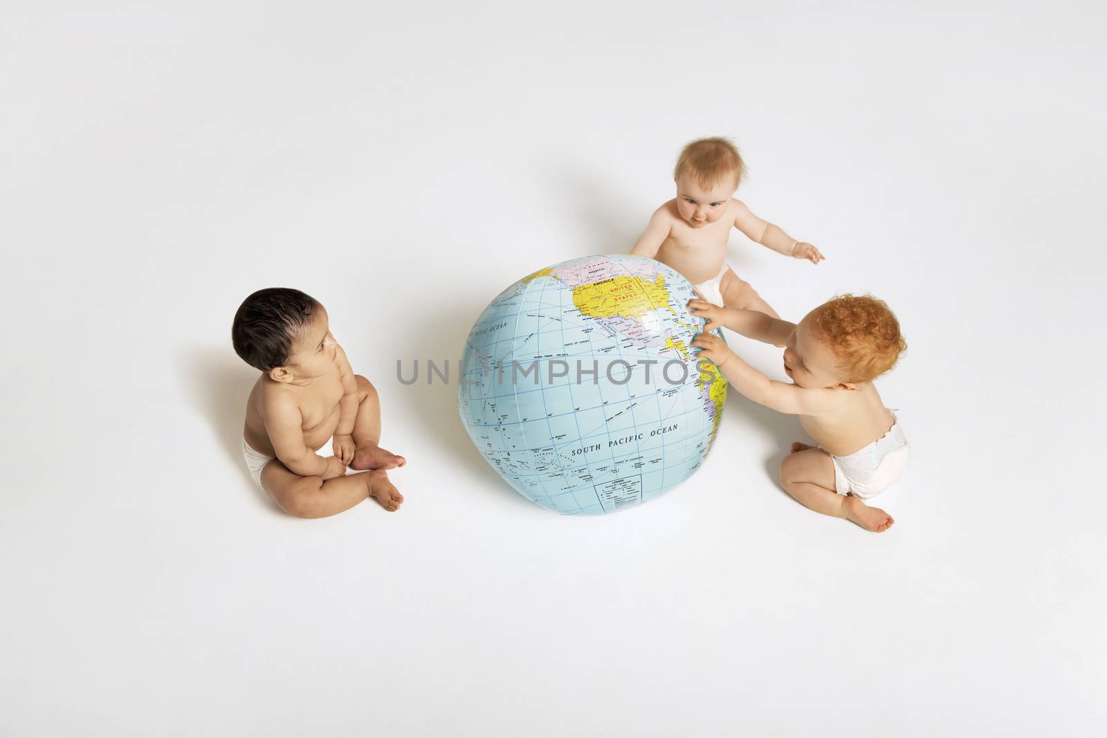 Multiethnic babies playing with globe isolated on white background by moodboard