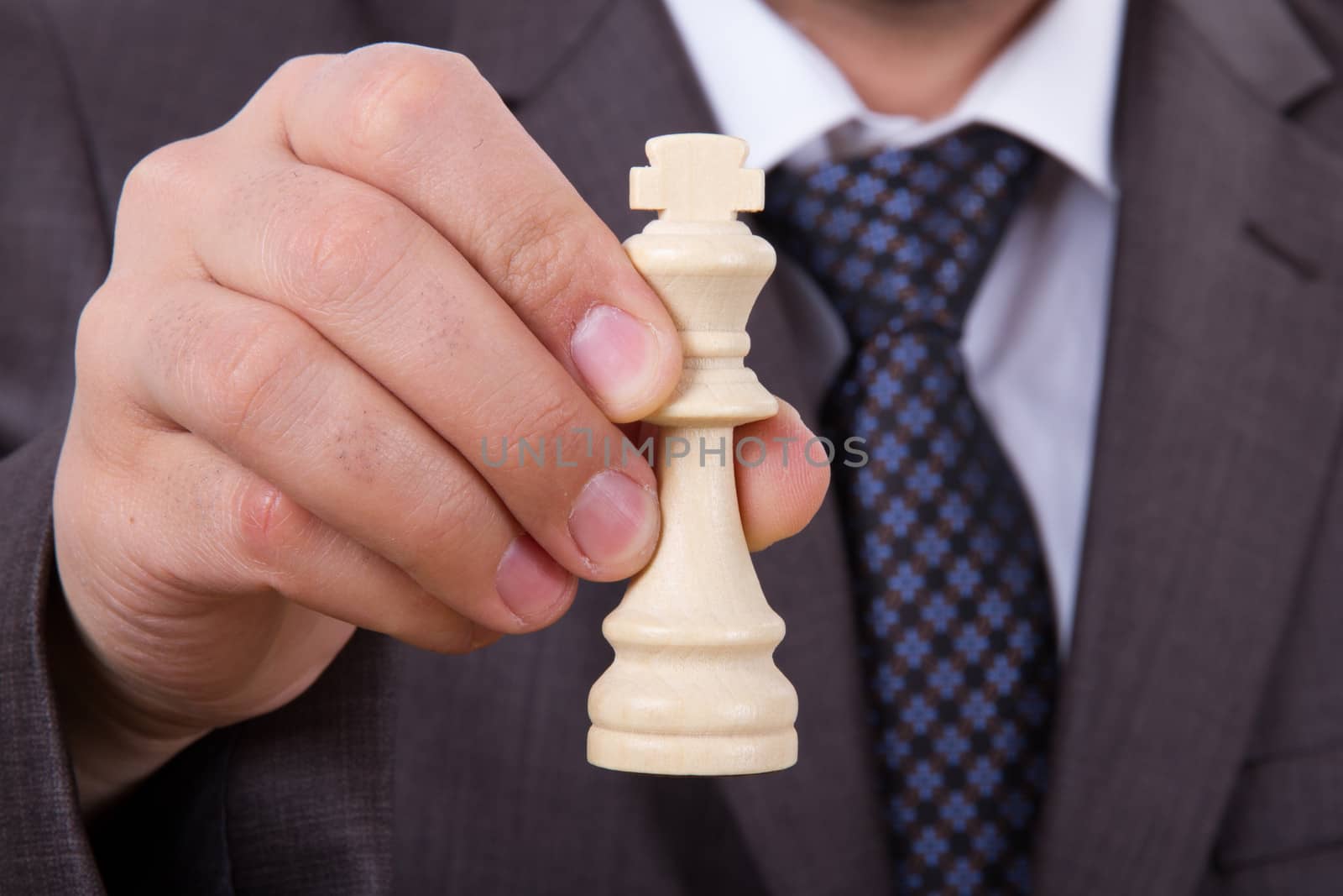 Businessman with formal clothes showing chess pieces, king.