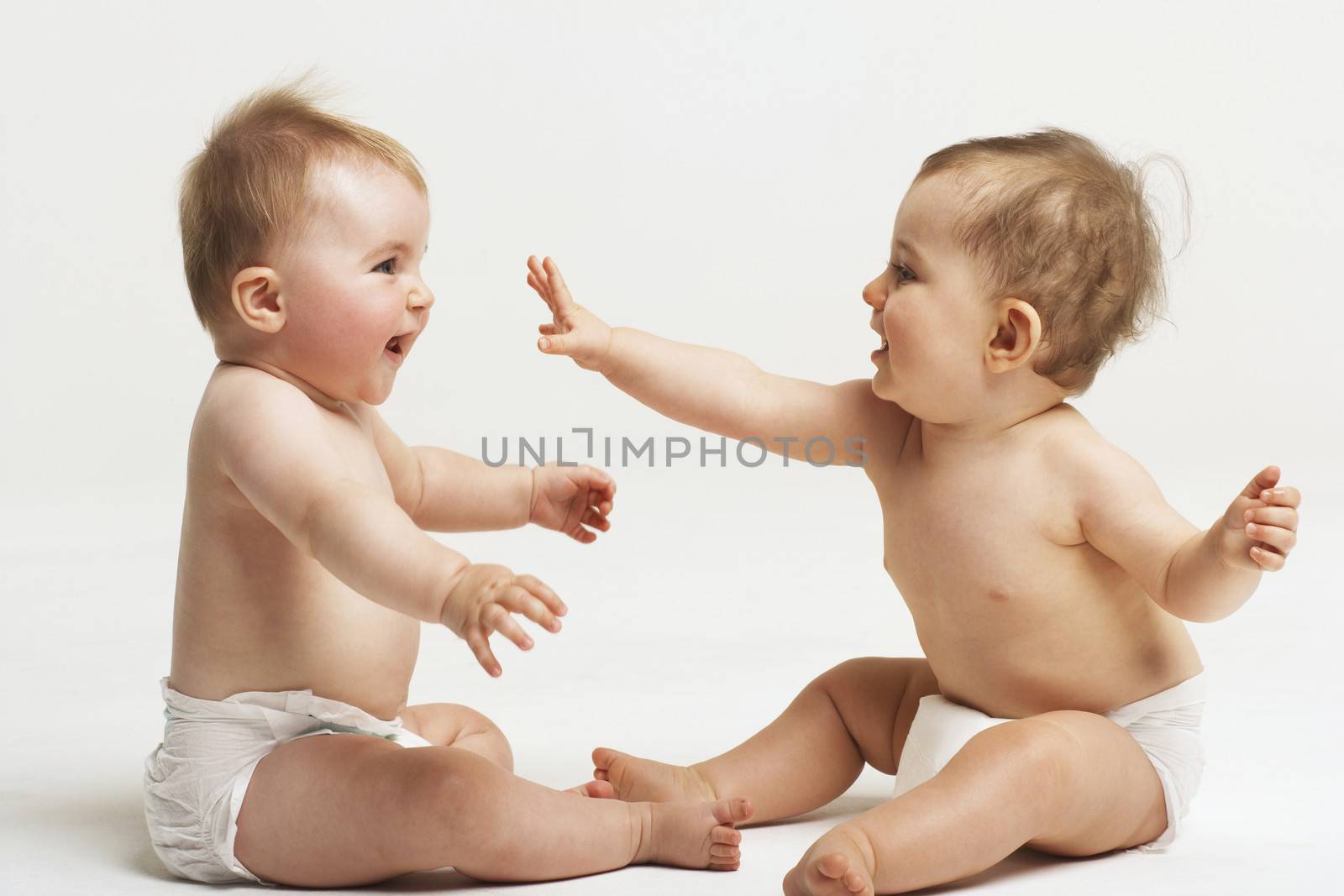 Side view of two babies playing on white background by moodboard