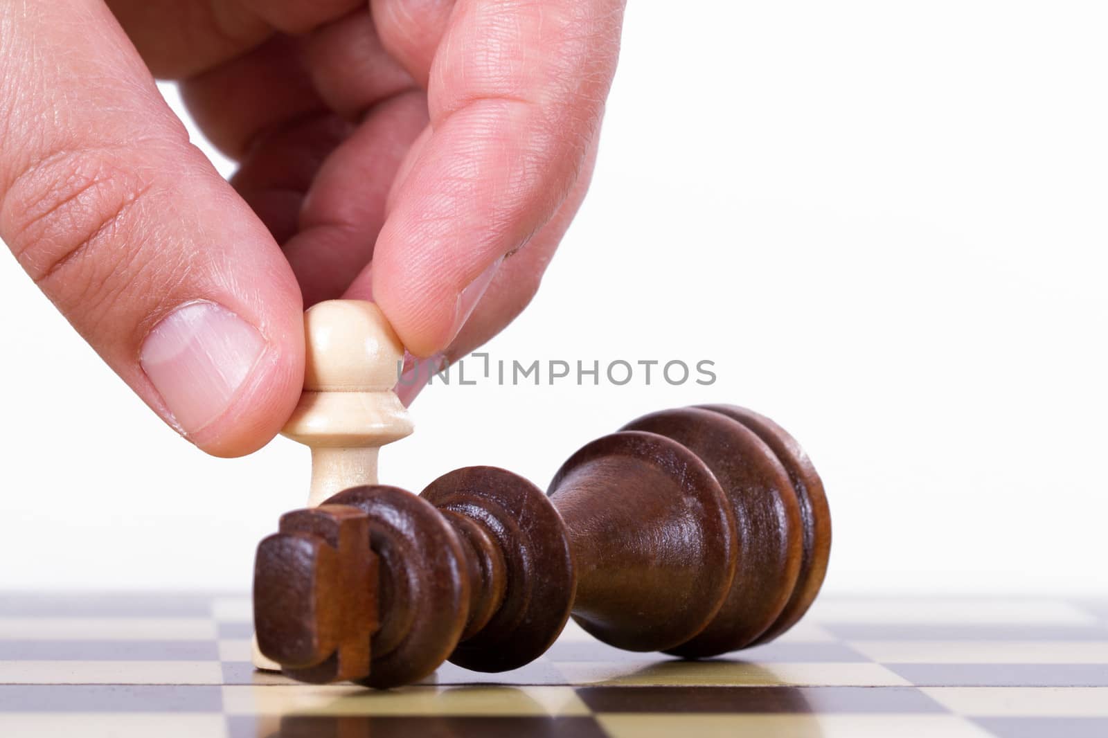 Victory concept, businessman holding pawn against king on chess board, isolated on white background.