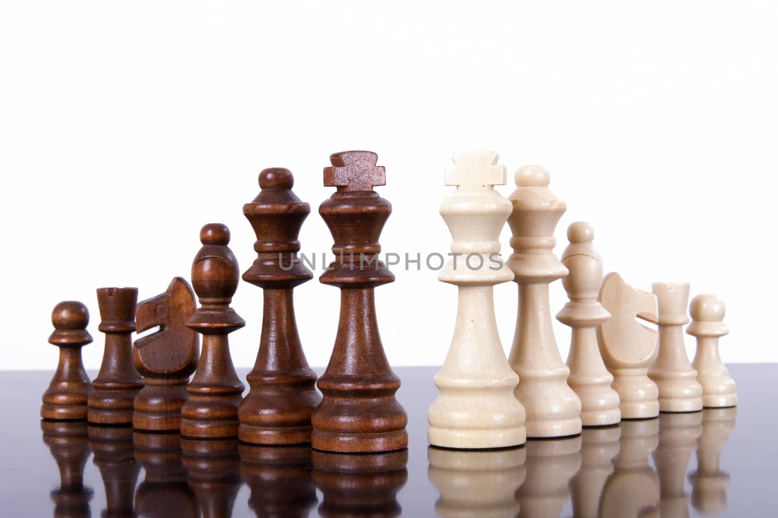Chess pieces in a row on dark table, isolated on white background.
