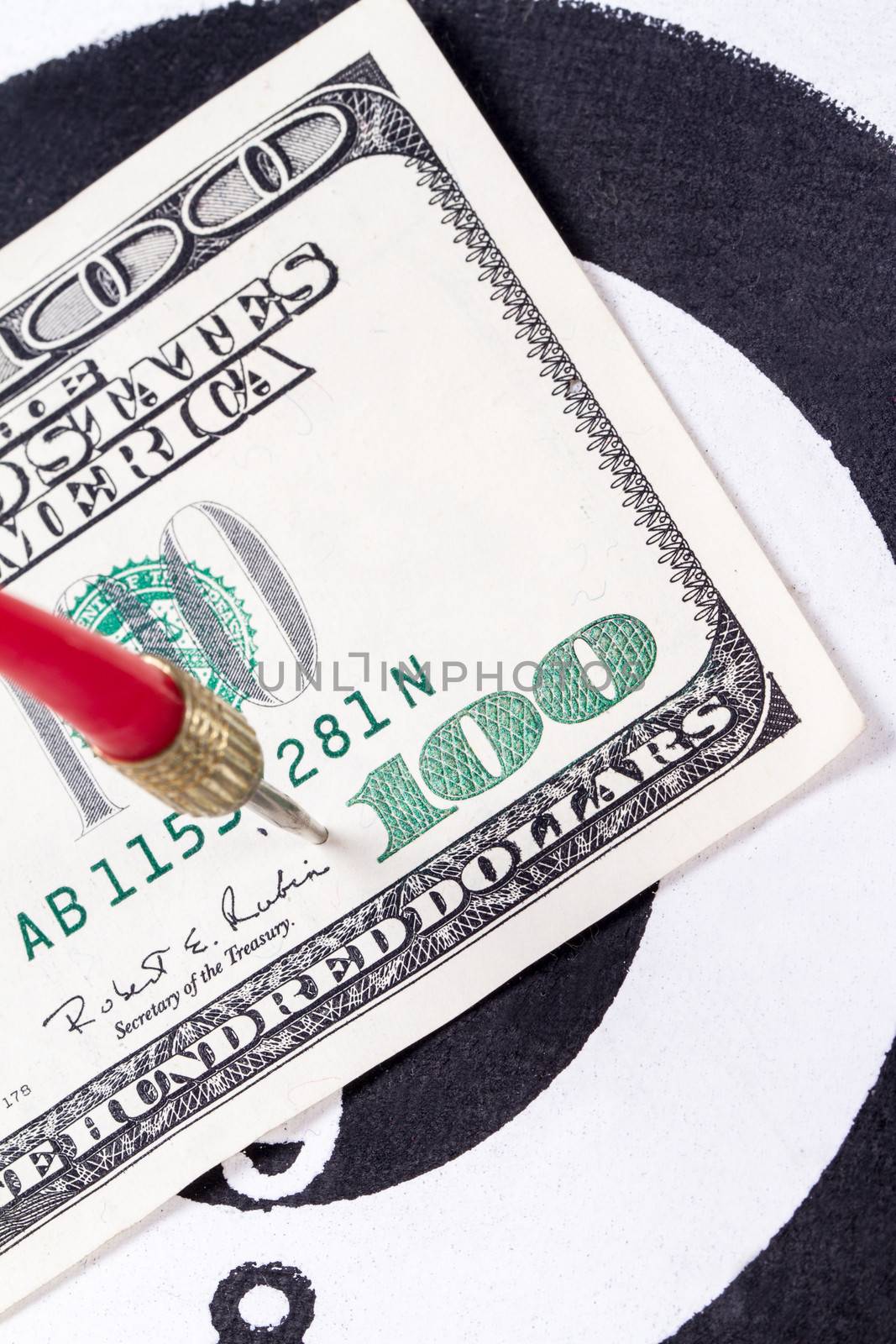 Red arrow and one hundred dollar bill on dart board.