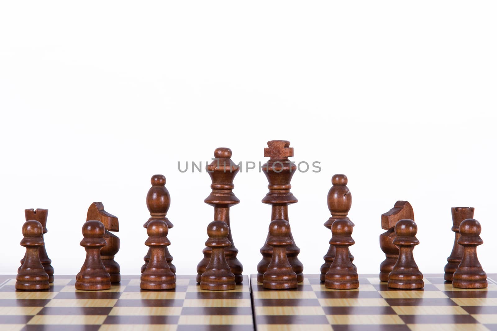 Full set of dark brown chess pieces on board, isolated on white background.