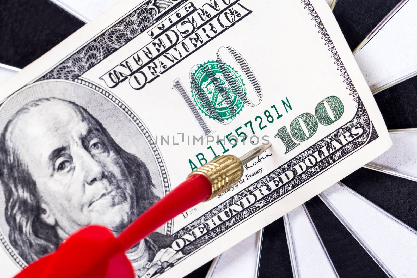 Close up view of red arrow and one hundred dollar bill on dart board.