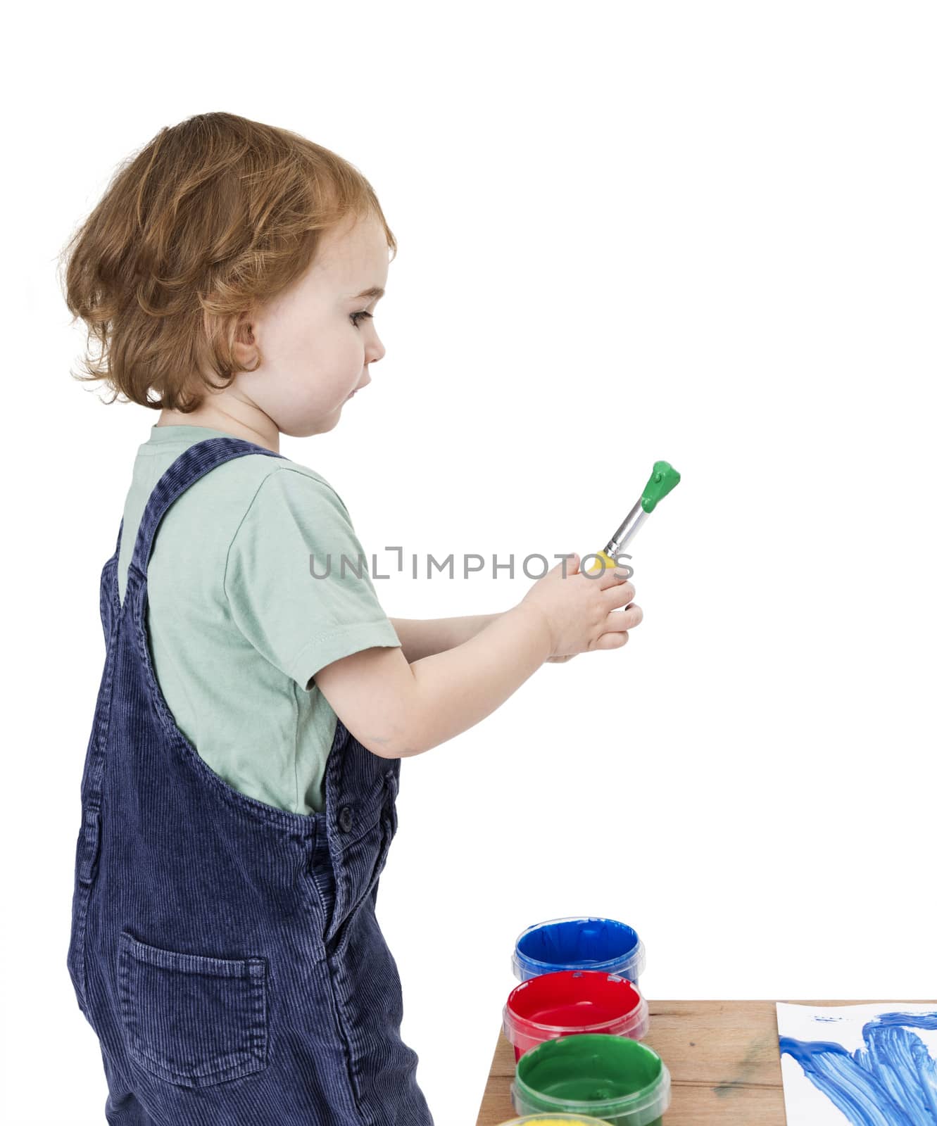 child with brush and green paint isolated on white background. Studio shot