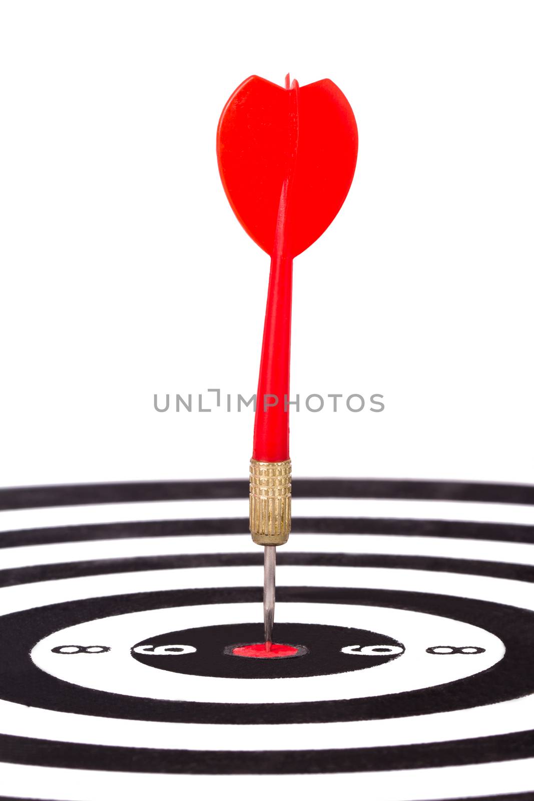 Red, plastic arrow hits middle of dart board, isolated on white background.