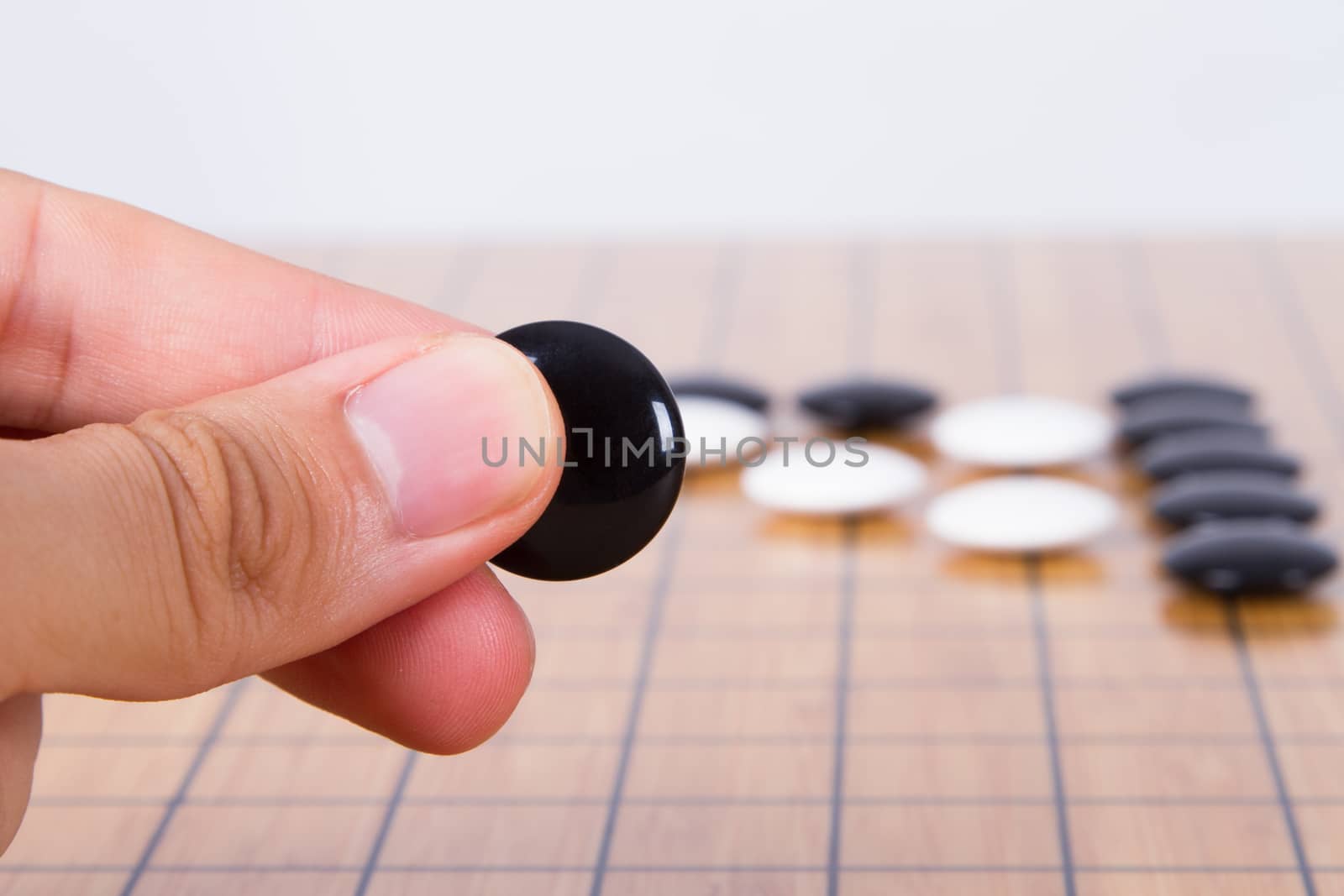 Close up view of hand playing black and white stone pieces on Chinese go game board.