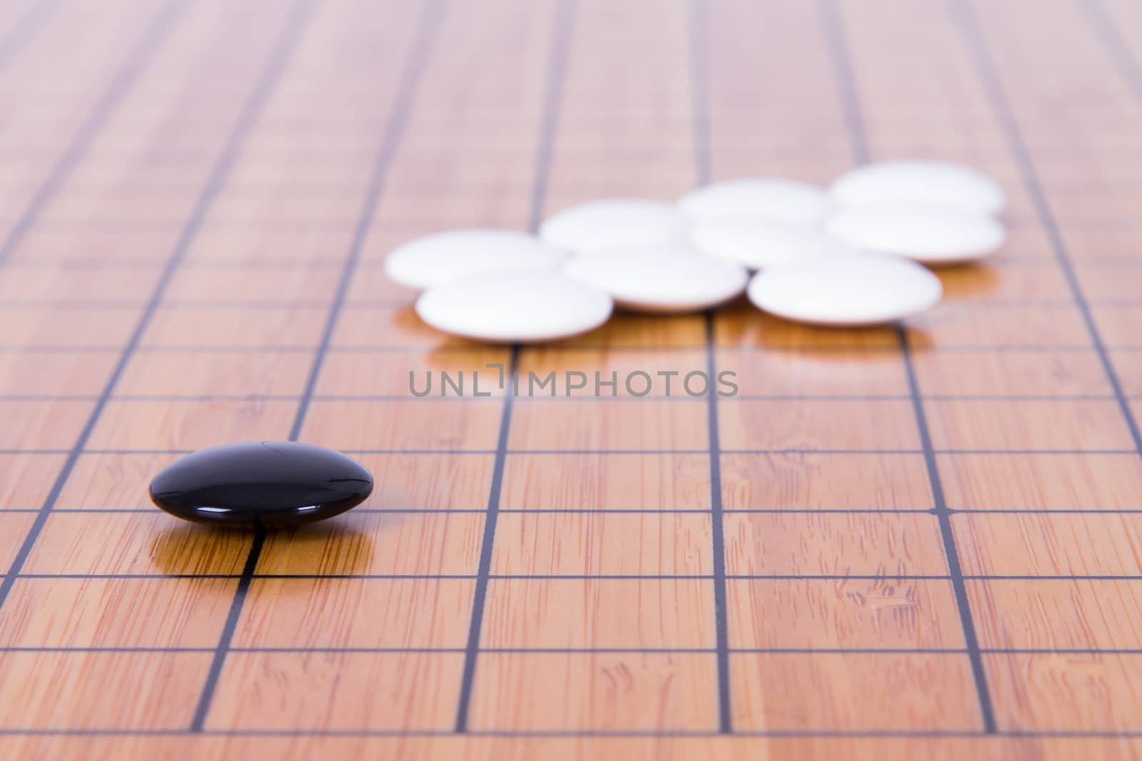 Black stone standing out from white pieces on Chinese go game board.