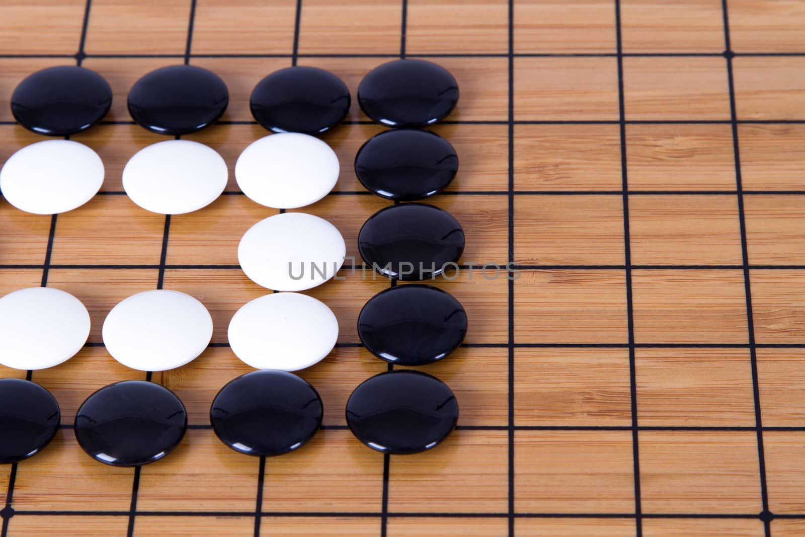 Close up view of black and white stone pieces on Chinese go game board.