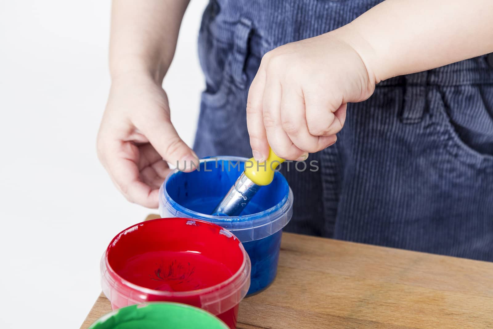 child holding brush in blue paint tub