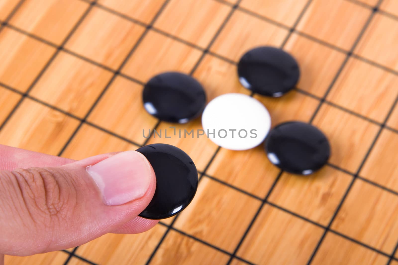 Close up view of hand playing black and white stone pieces on Chinese go game board.