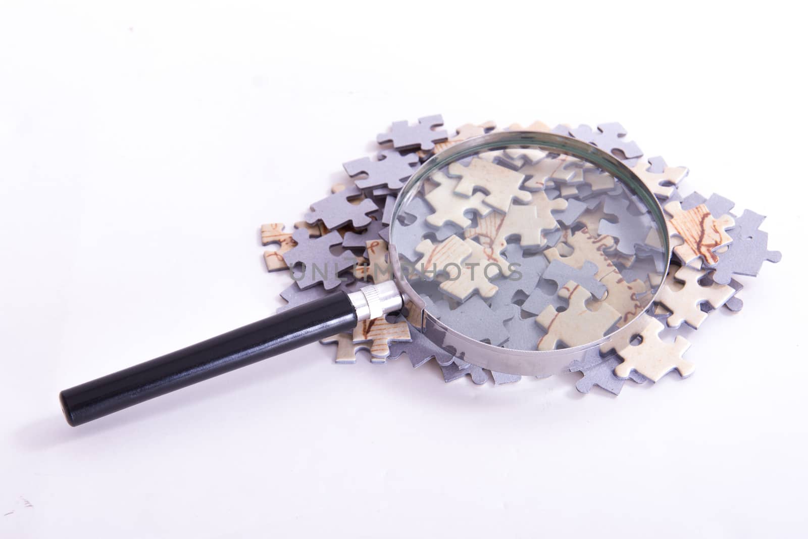Classic style magnifying glass on little puzzle pieces, isolated on white background.