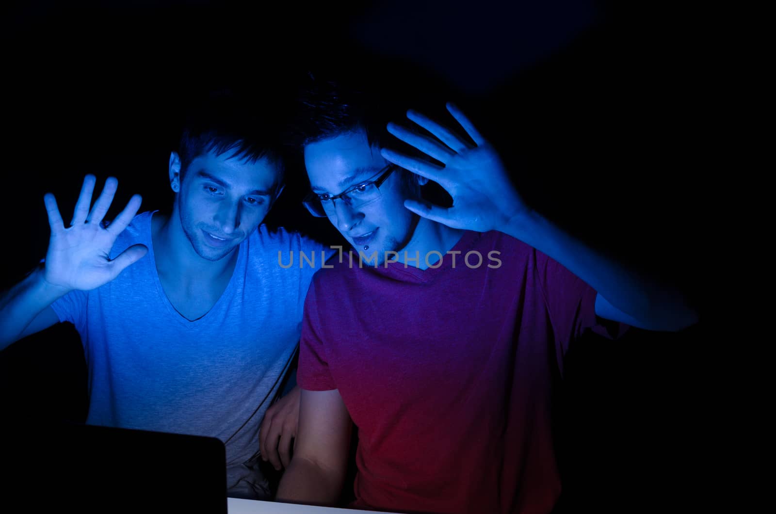 Two guys greeting someone through a video chat