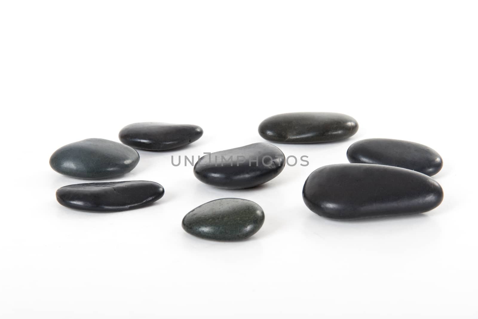 Black massage stones, isolated on white background.
