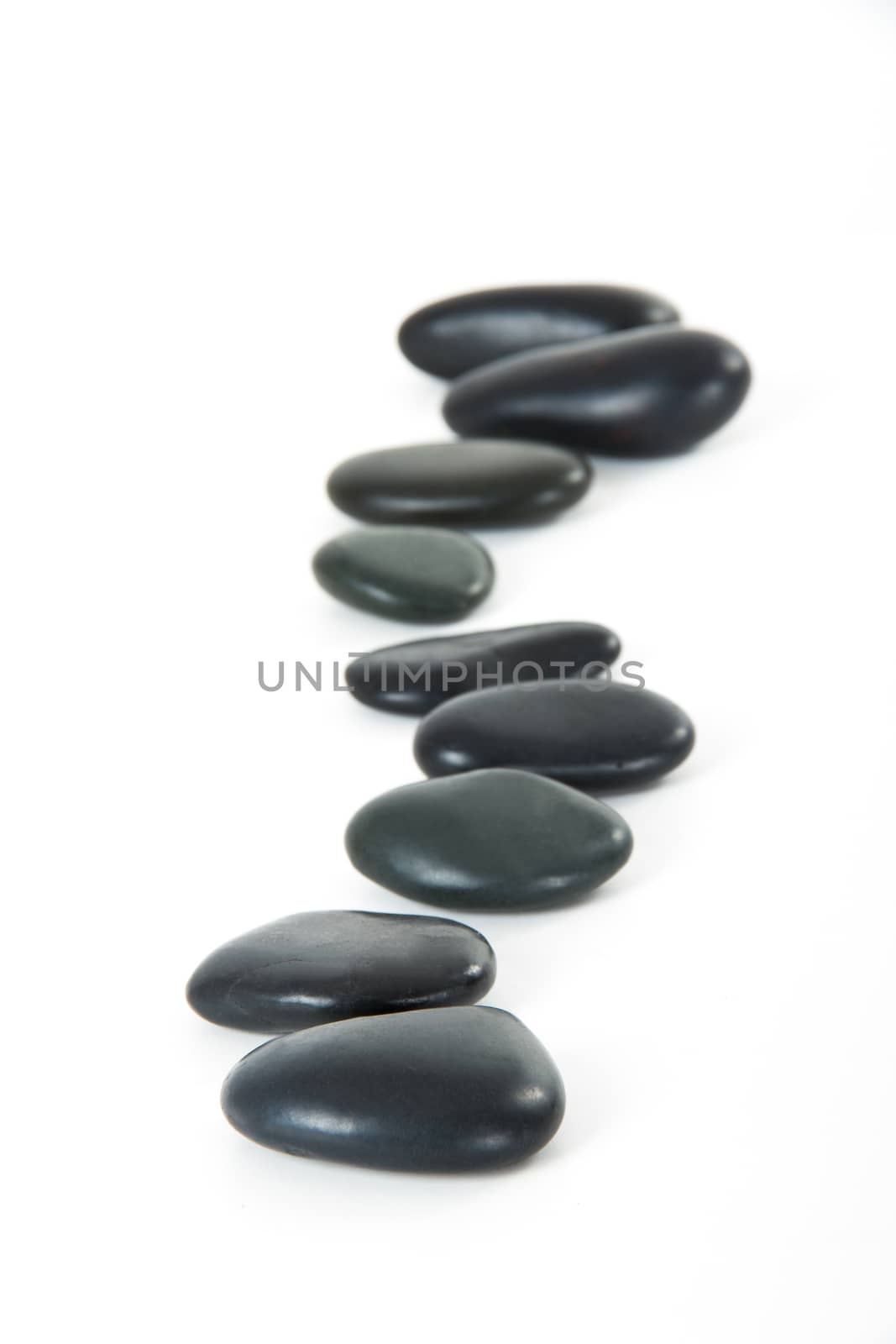 Black massage stones in a row, isolated on white background.