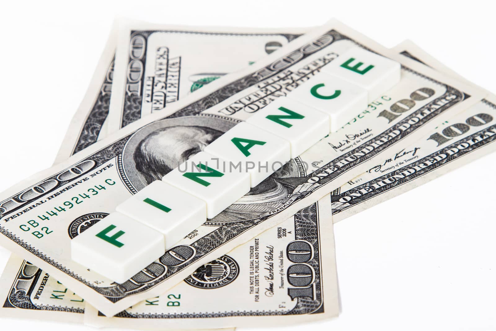 Finance word in letters and one hundred dollar bills, isolated on white background.