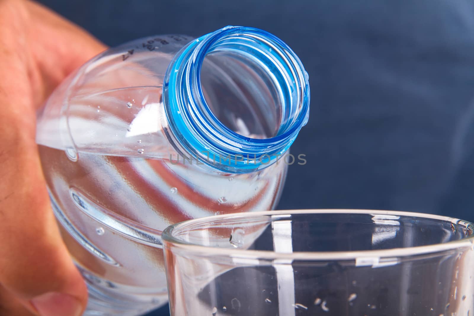 Water pouring into glass from plastic bottle.