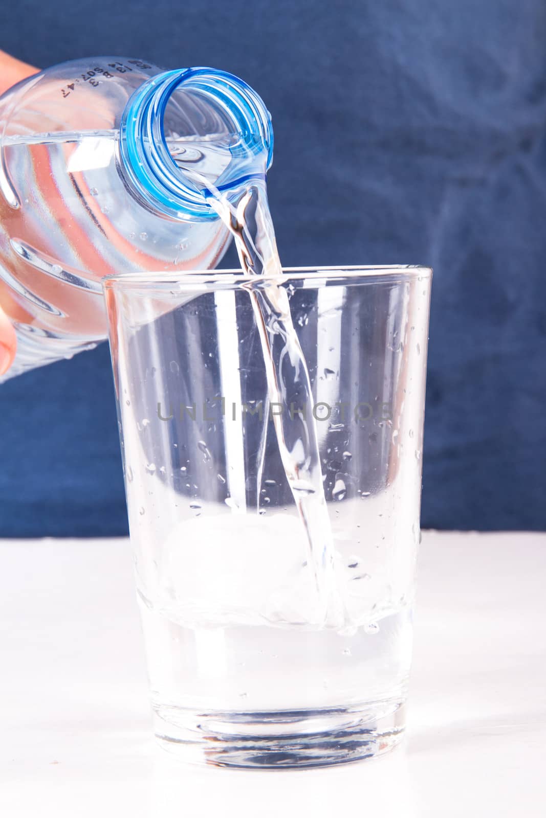 Pouring water into glass from plastic bottle.