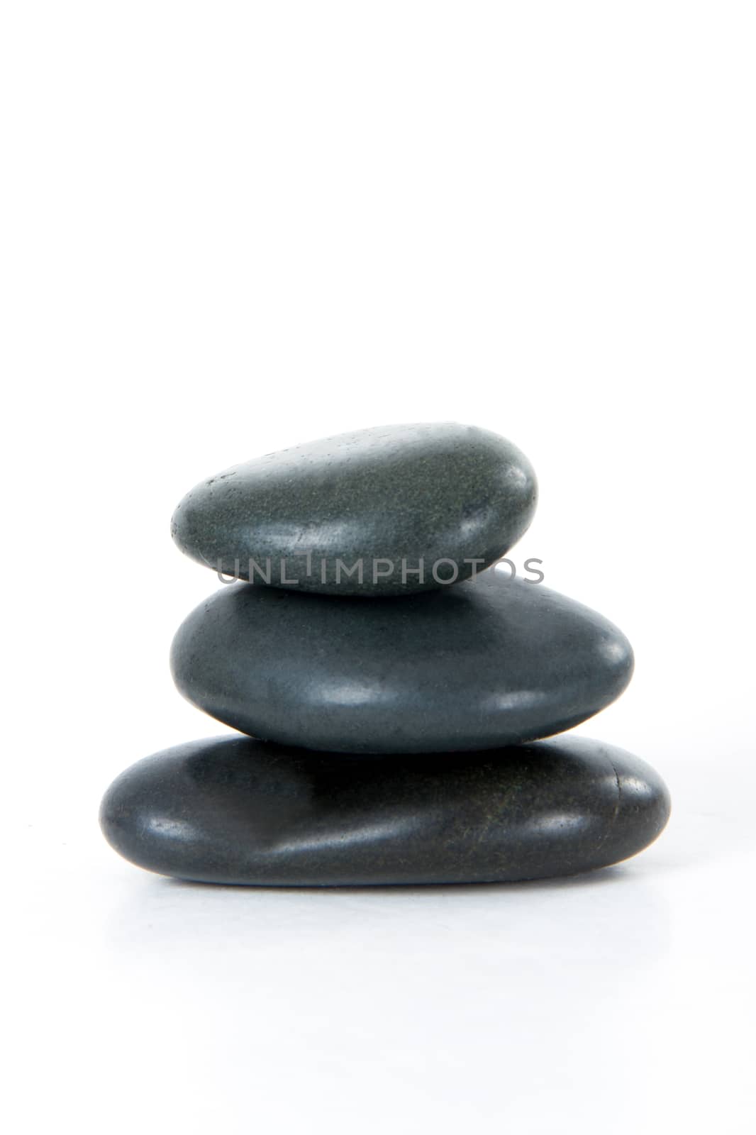 Stack of three black massage stones, isolated on white background.