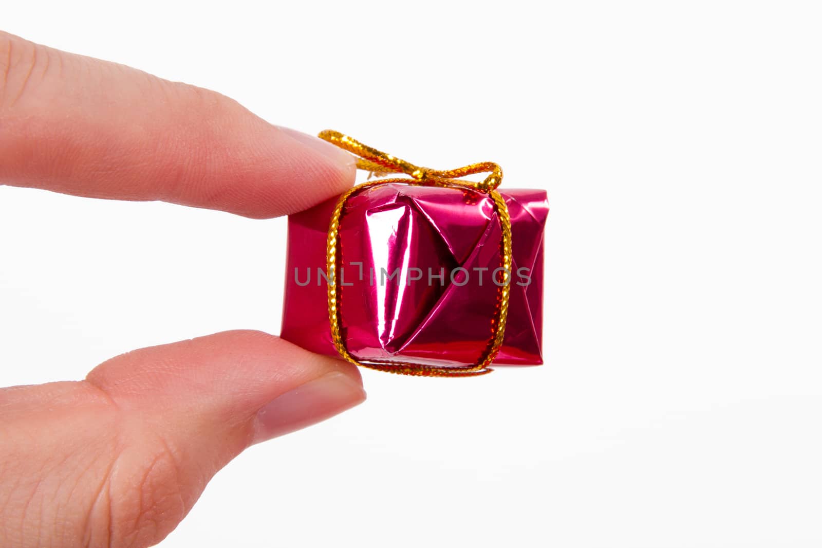 Little, beautiful gift holding by two fingers, isolated on white background.