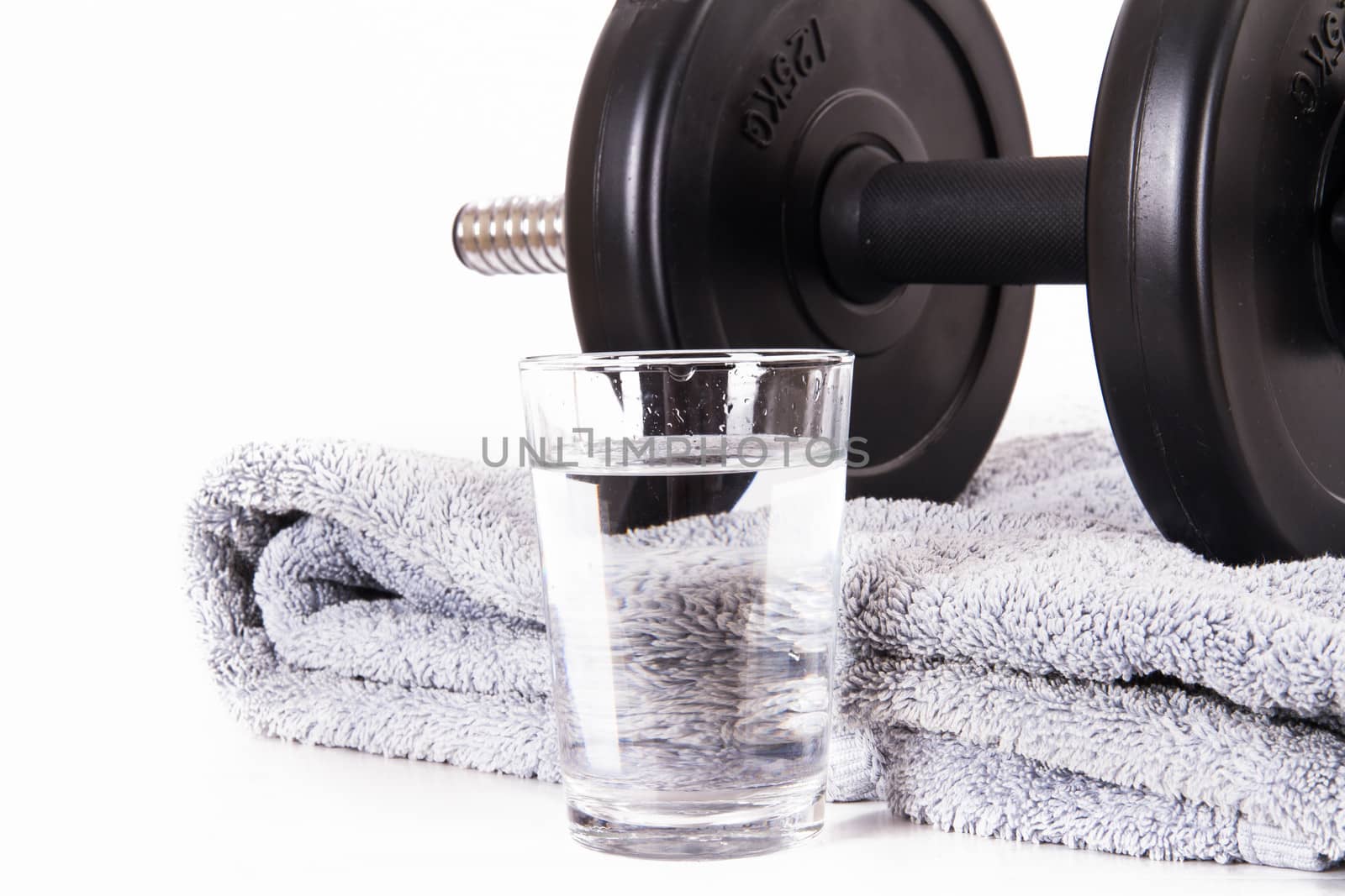 Black gym barbell, dumbbell with disks, blue towel and glass of water, isolated on white background.