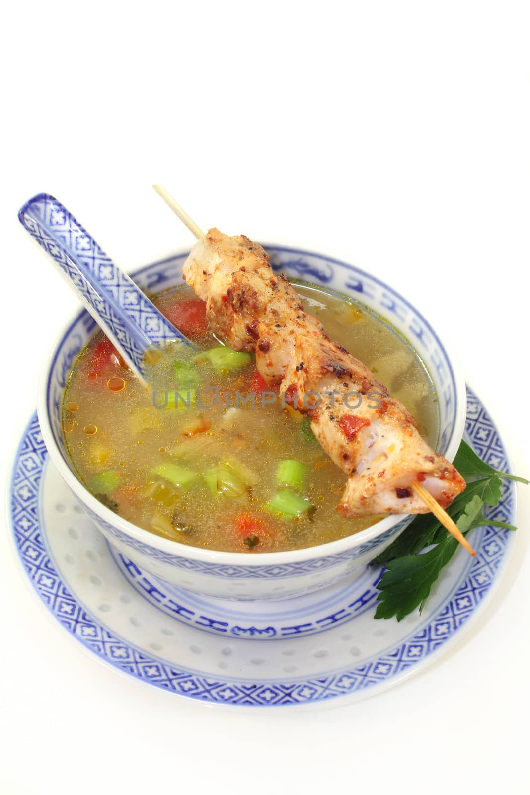 a bowl of chicken consomme and a chicken skewer