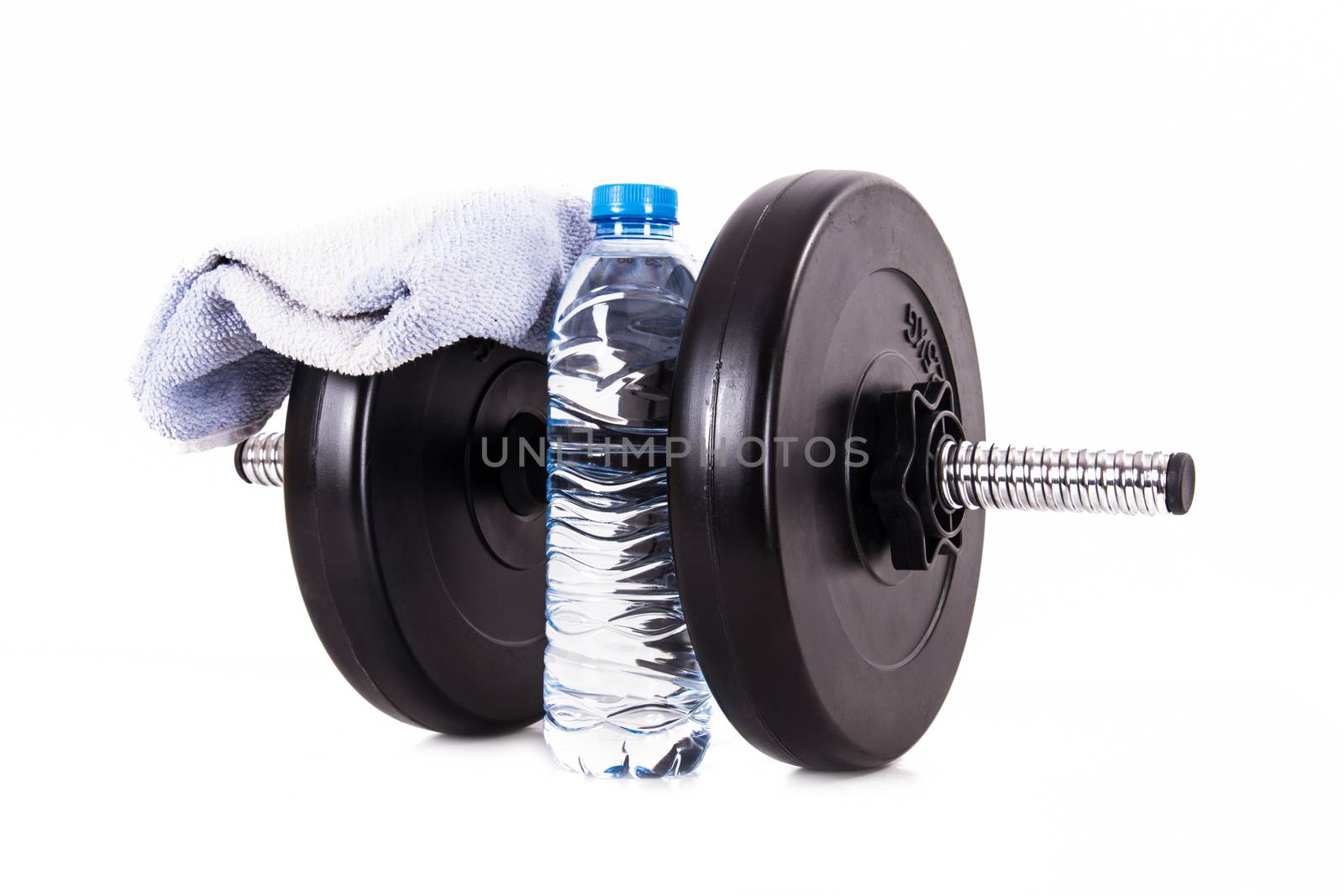 Black dumbbell with blue towel and plastic water bottle, isolated on white background.