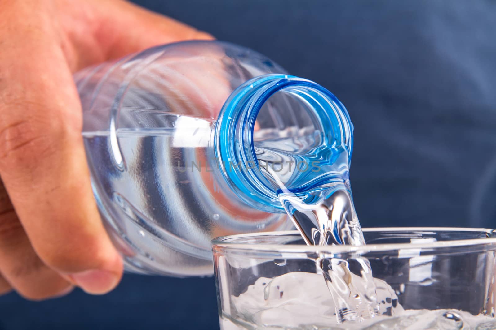 Water pouring into glass from plastic bottle.