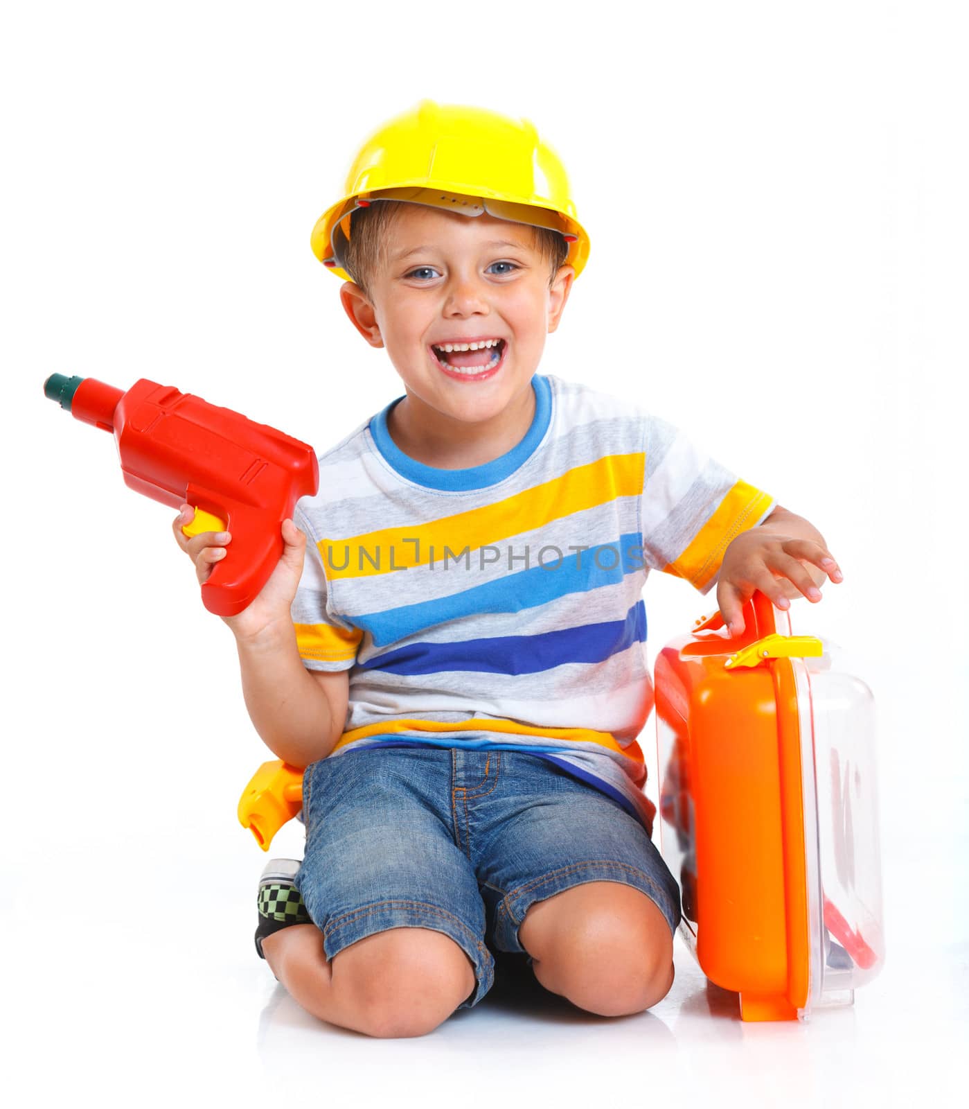 Little builder. Boy in a helmet plays in the builder with tools. Isolated over white.